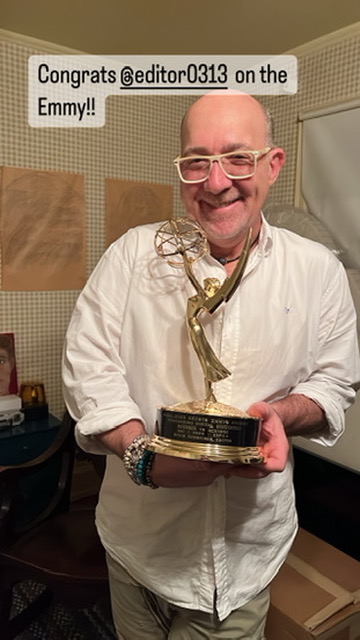 Mitch smiling with an Emmy trophy